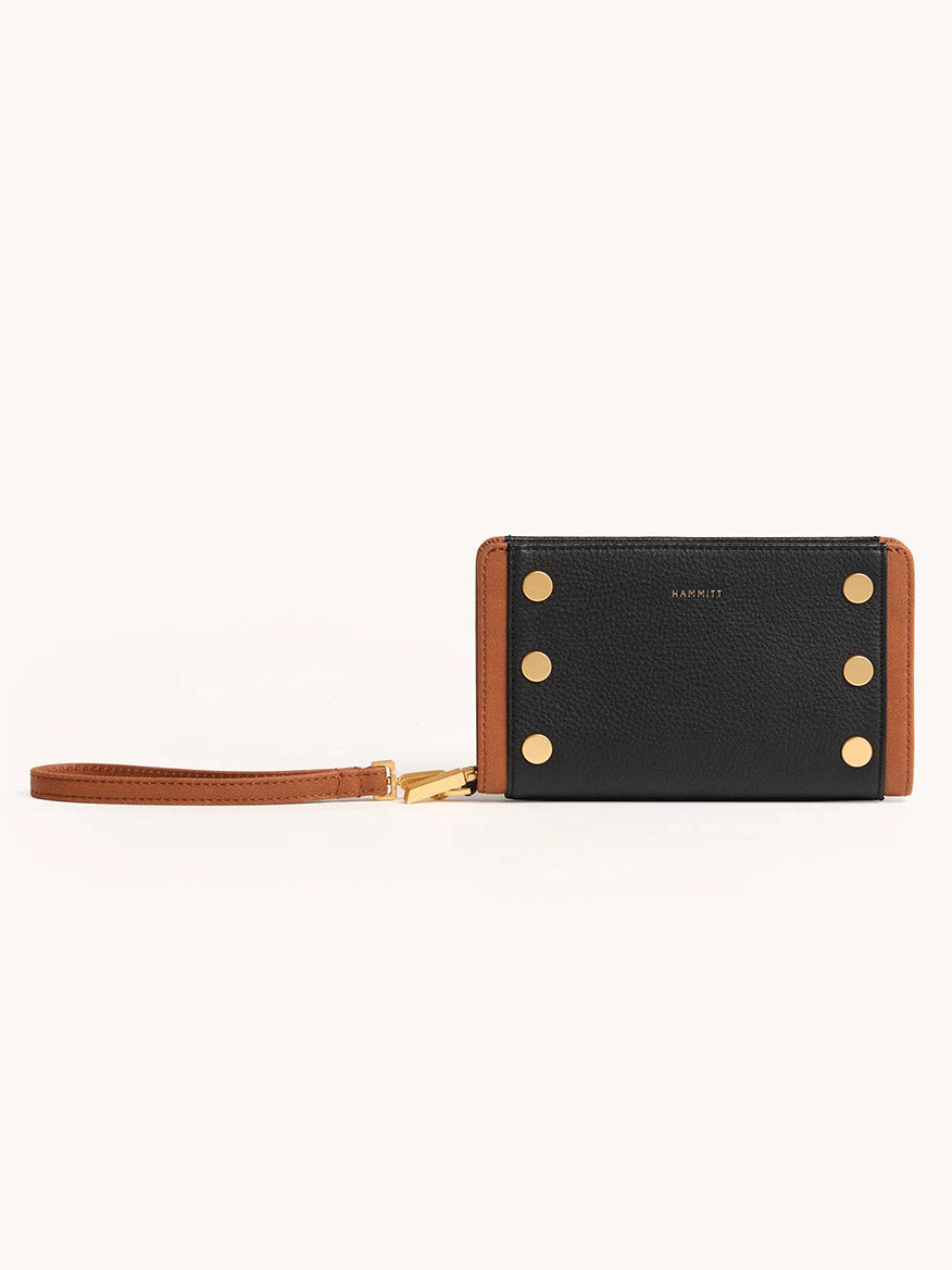 The Hammitt Los Angeles Bryant Wallet in North End features black leather and brown accents, gold metal studs, a detachable wrist strap, and a sleek continental design, shown against a plain background.