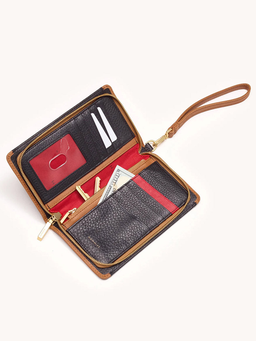 An open Hammitt Los Angeles Bryant Wallet in North End with a wrist strap displays cash, a red credit card, two white cards, a zipper compartment, and multiple card slots in a sleek continental design on a light background.
