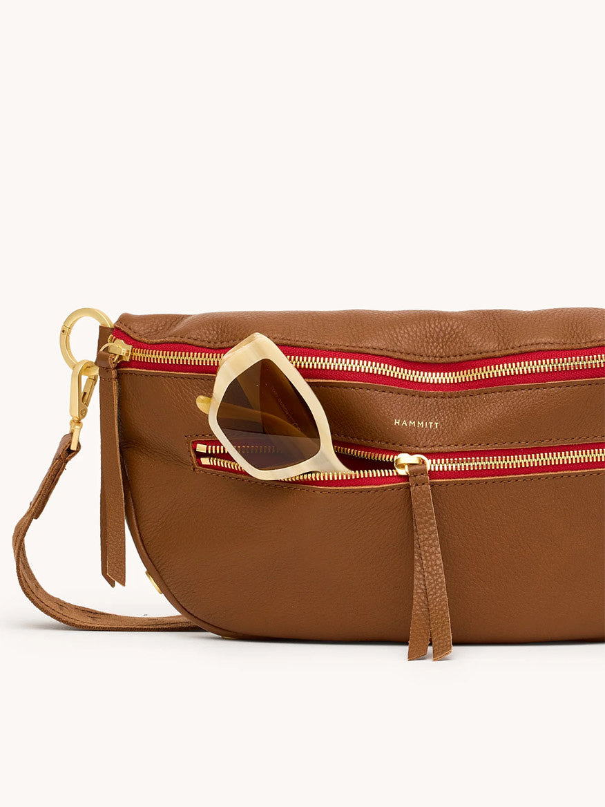 The Hammitt Los Angeles Charles Crossbody Large in Mahogany Pebble/Brushed Gold & Red Zip features gold hardware and a front zip pocket, perfect for essentials like sunglasses.