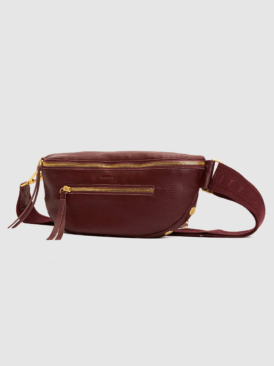 The Hammitt Los Angeles Charles Crossbody Medium in Cherrywood Pebble/Brushed Gold, featuring gold zippers and a wide adjustable strap, is displayed against a plain light gray background.