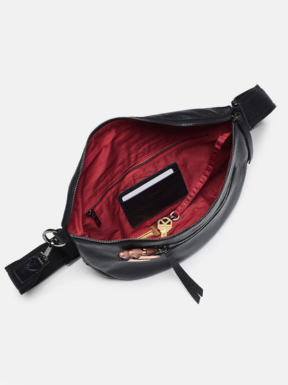 Hammitt Los Angeles Charles Crossbody Large in Black fanny pack open to reveal red interior with a credit card and coins inside, isolated on a white background.