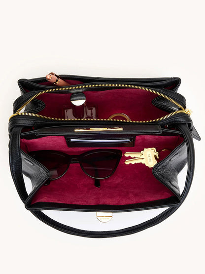 The Hammitt Los Angeles Charlotte Medium in Black/Gold, crafted from black pebble leather with a red interior, fits sunglasses, keys, lipstick, and a bottle. Its open design reveals roomy organized compartments for daily essentials.
