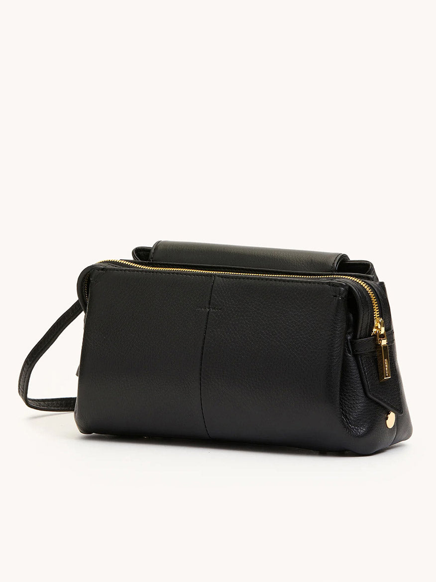 The Hammitt Los Angeles Charlotte Medium in Black/Brushed Gold features plush pebble leather, gold zipper accents, and a slim strap, shown against a plain light background.