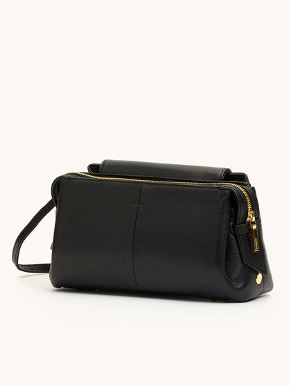 The Hammitt Los Angeles Charlotte Medium in Black/Brushed Gold features plush pebble leather, gold zipper accents, and a slim strap, shown against a plain light background.
