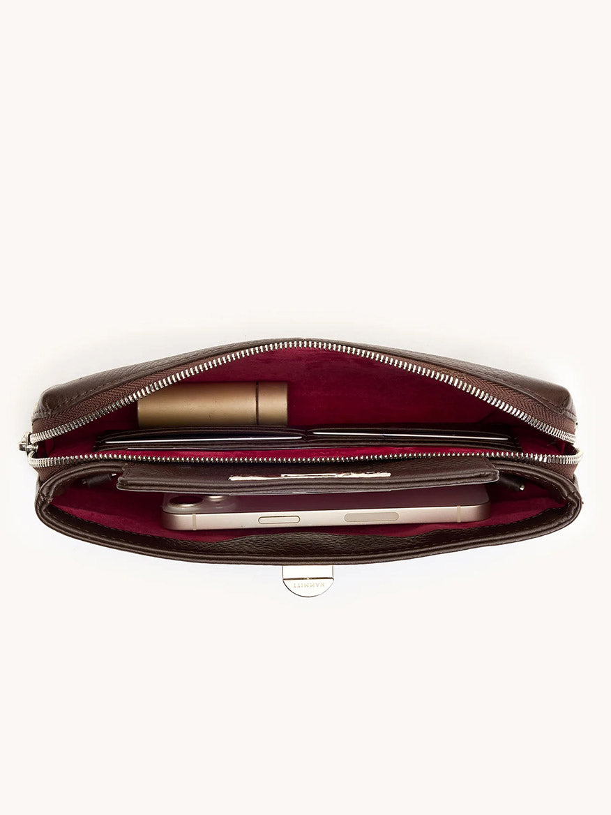 The Hammitt Los Angeles Charlotte Small in Espresso Pebble/Silver is shown from above, revealing a burgundy interior that holds a phone, a pen, and a small cylindrical item.
