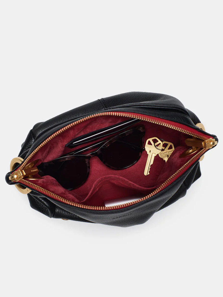 Open Hammitt Los Angeles Daniel Crossbody Clutch Small in Black & Brushed Gold, showing a red interior with sunglasses and keys inside.