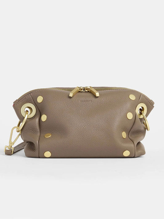 Presenting the Hammitt Los Angeles Daniel Crossbody Clutch Small in Sculpted Taupe—a taupe leather piece with pebbled texture, zip closure, and gold hardware. It shines with circular studs and rings on the sides.