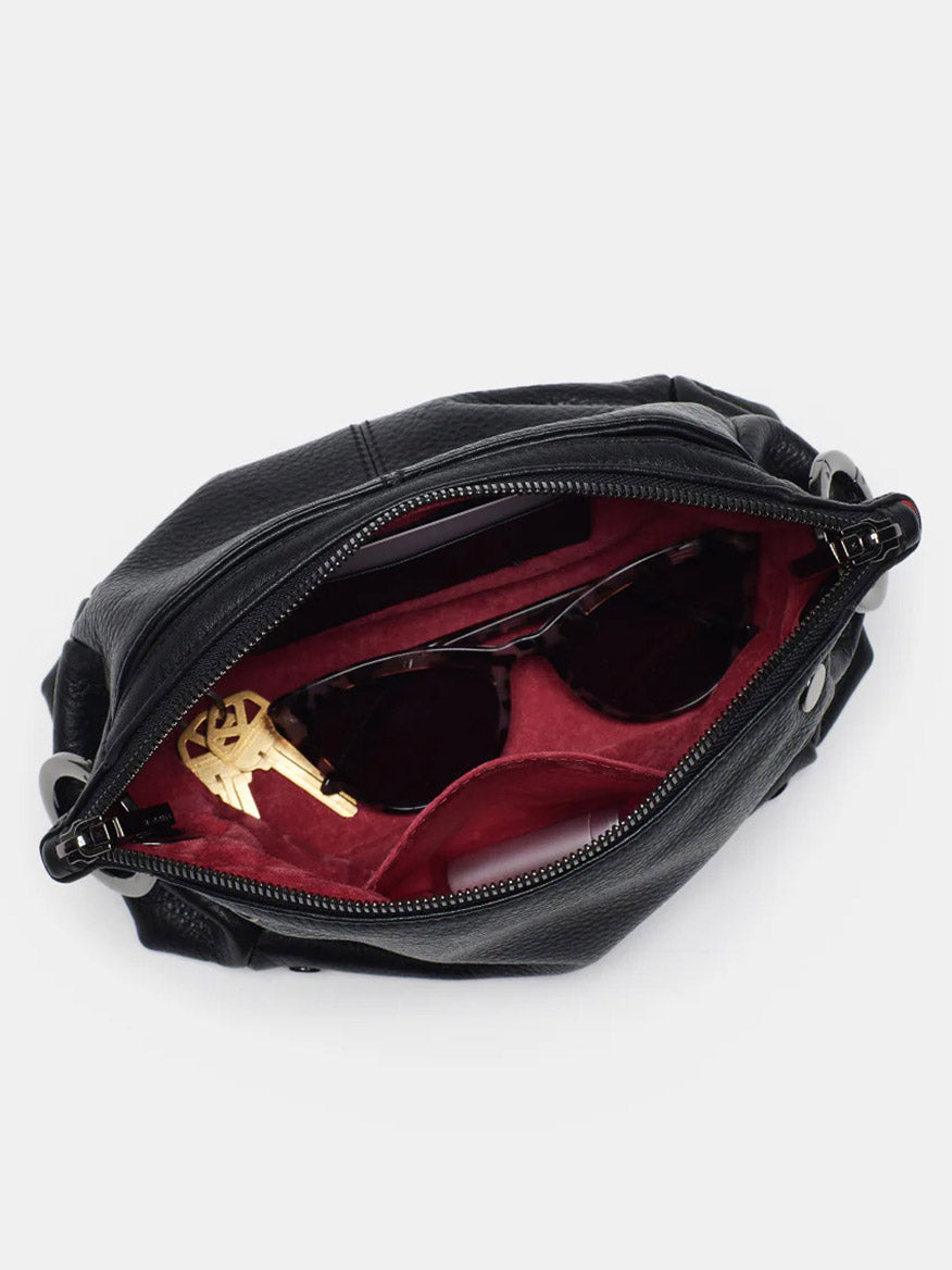 A Hammitt Los Angeles Daniel Crossbody Clutch Small in Black, featuring red interior and gunmetal hardware, contains sunglasses and a gold-colored key.