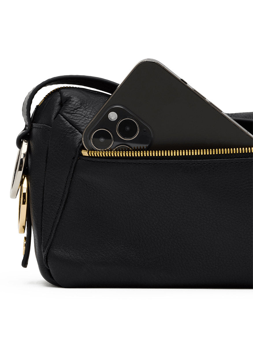 The Hammitt Los Angeles Doxie Medium in Black/Gold/Silver, featuring black pebbled leather and gold hardware, with a black smartphone partially visible in its front zippered pocket.