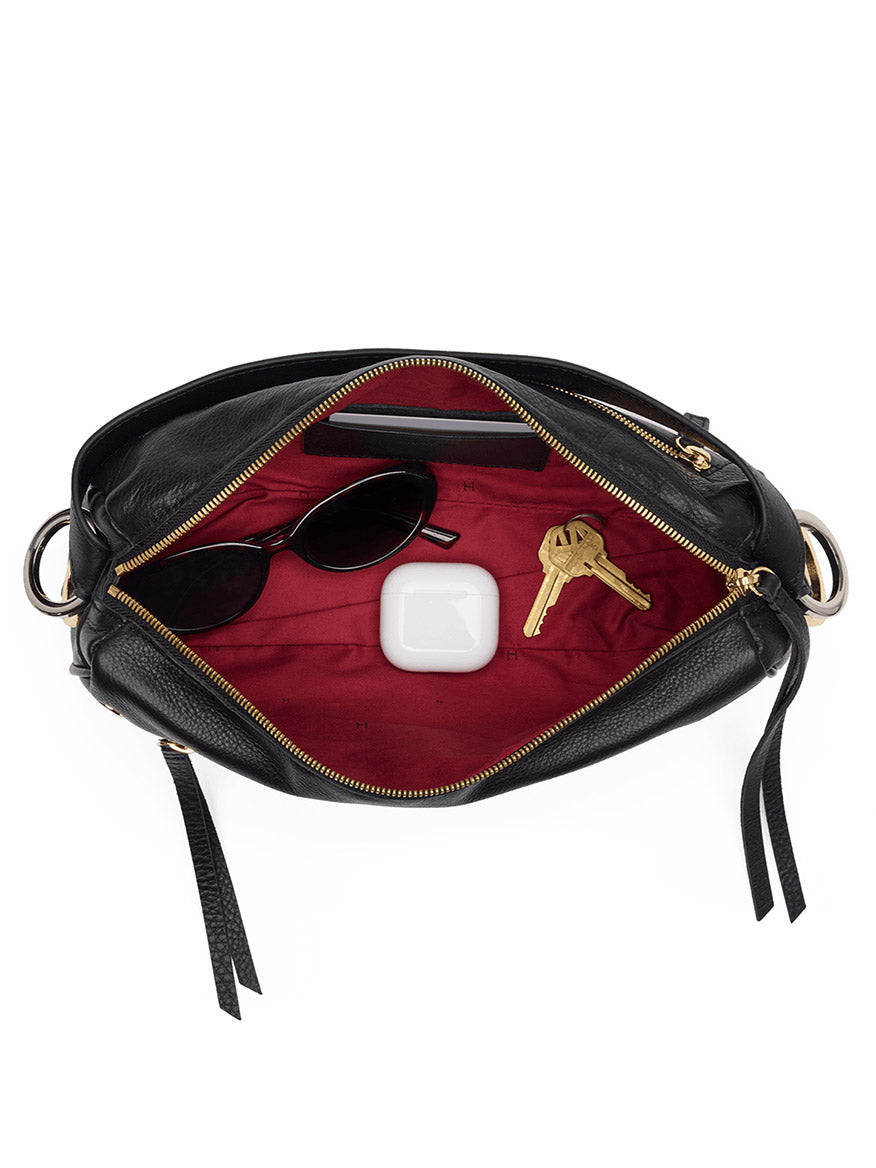 Open Hammitt Los Angeles Doxie Medium in Black/Gold/Silver—with black pebbled leather, red interior, and mixed-metal hardware—carrying sunglasses, a pair of keys, and a white wireless earbud case.