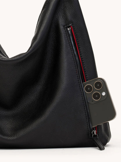 A black/gunmetal Hammitt Los Angeles Kyle Large Shoulder Bag features a partially open zipper pocket with a smartphone inside, highlighting its stylish and practical design.