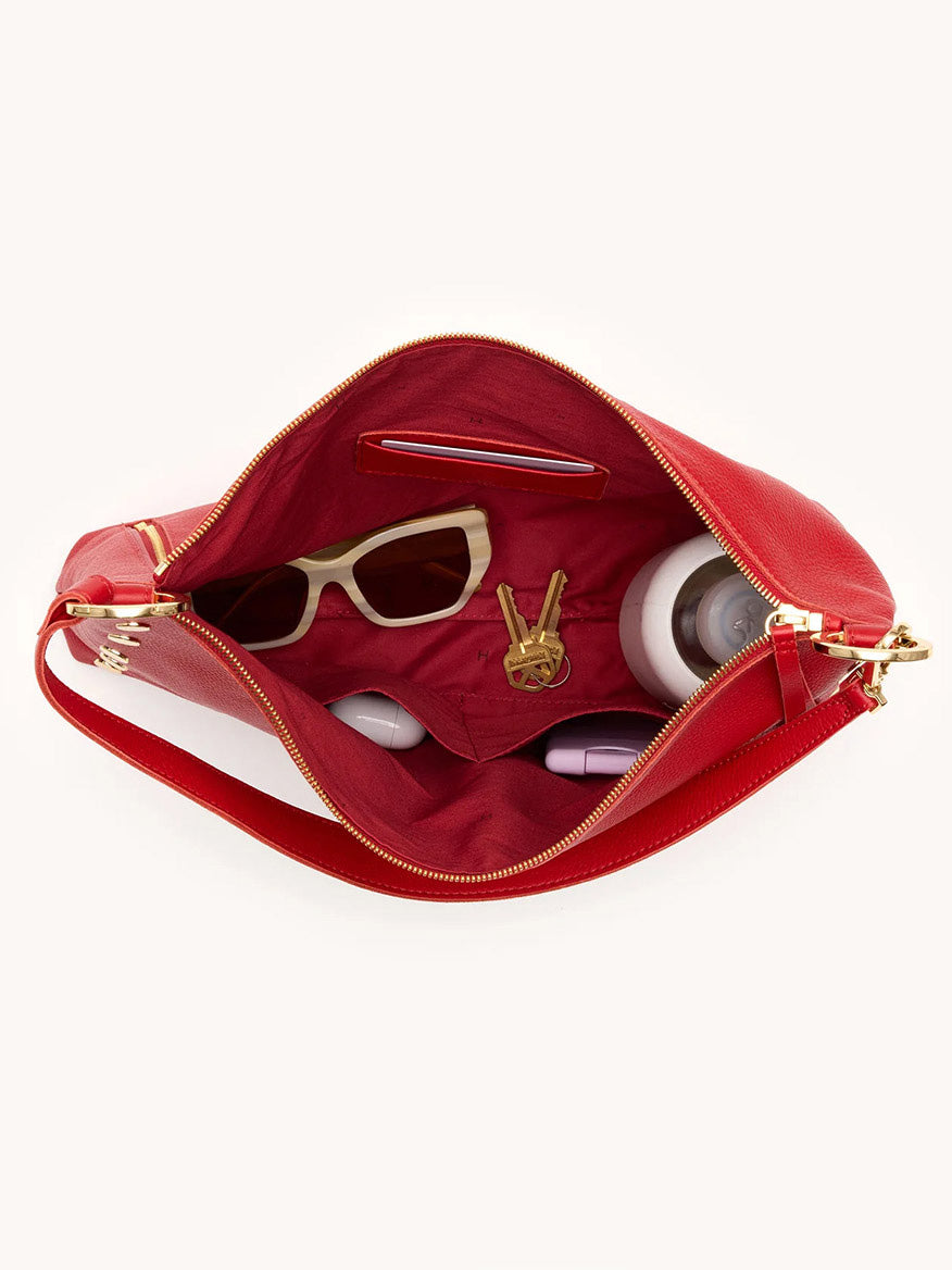 Open the Hammitt Los Angeles Kyle Large Shoulder Bag in Chili Red/Gold, viewed from above, with sunglasses, keys, water bottle, phone, lipstick, and a small electronic device inside.