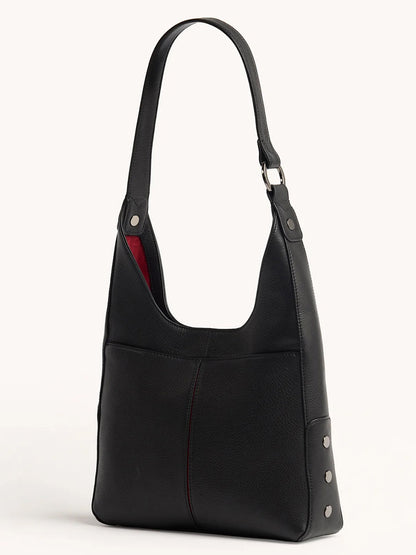 The Hammitt Los Angeles Tim Hobo in Black is a pebbled leather shoulder bag featuring a single strap, front pocket, visible stitching, silver side rivets, magnetic closure, and a red interior lining.