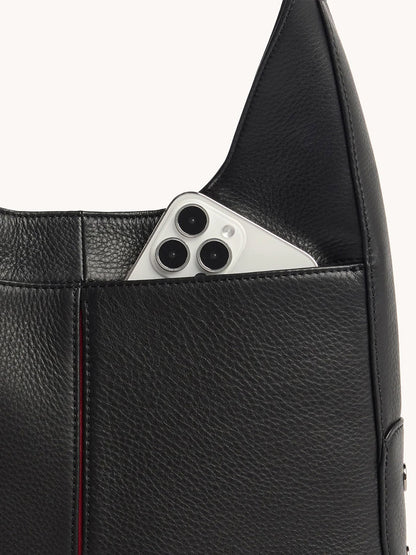 The Hammitt Los Angeles Tim Hobo in Black, crafted from pebbled leather with an exterior pocket and magnetic closure, securely holds a silver smartphone with three camera lenses.