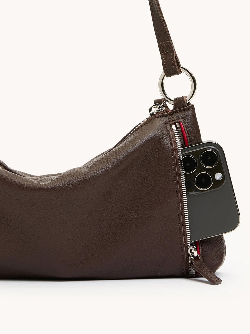 A Hammitt Los Angeles Kyle Shoulder Bag in Espresso Pebble/Silver features a partially open zipper pocket, revealing a smartphone inside.
