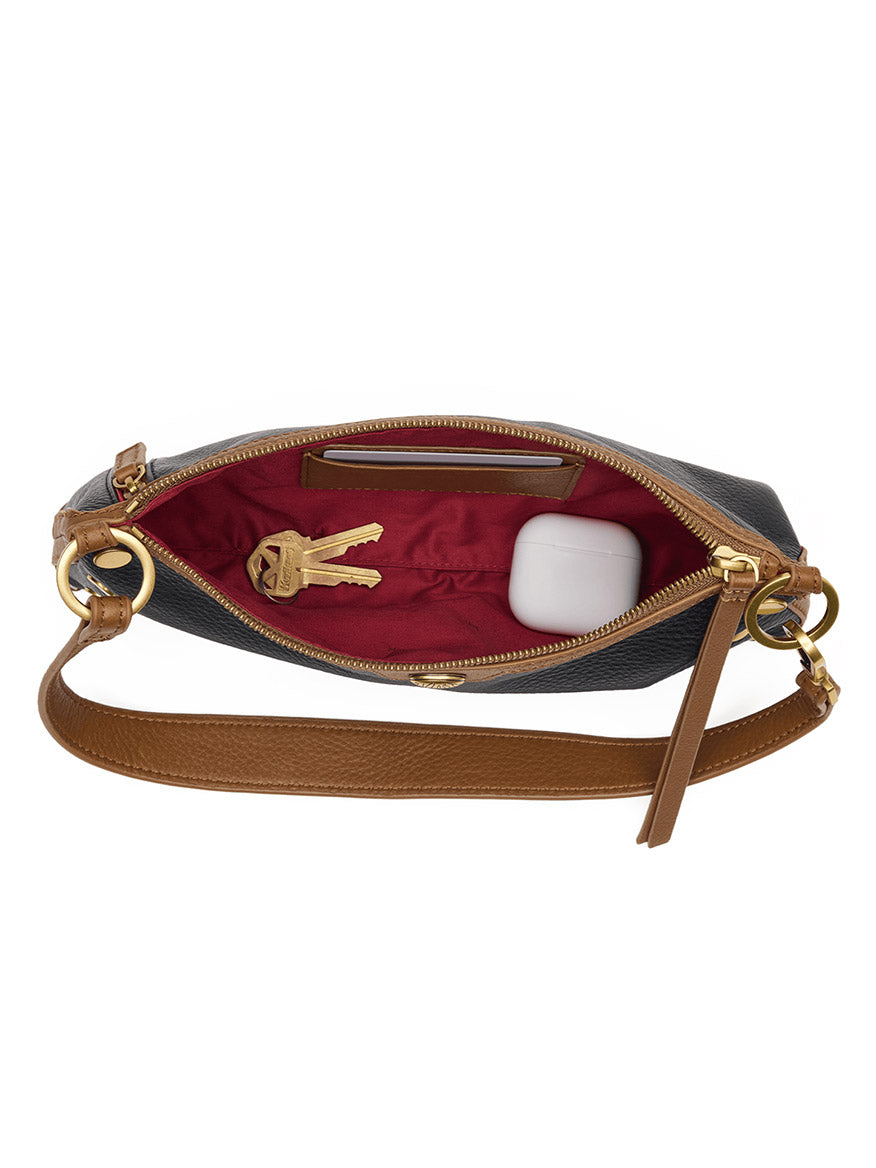 The Hammitt Los Angeles Kyle Shoulder Bag in East End/Antique Gold, with an open design, features a brown strap and is crafted from black pebbled leather. Its red interior holds a set of keys and a white wireless earbud case.