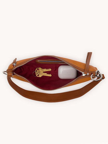 Open Hammitt Los Angeles Kyle Shoulder Bag in Tailored Tangerine/Silver, showing a maroon interior with a set of keys and a white rectangular item, possibly a charging case.