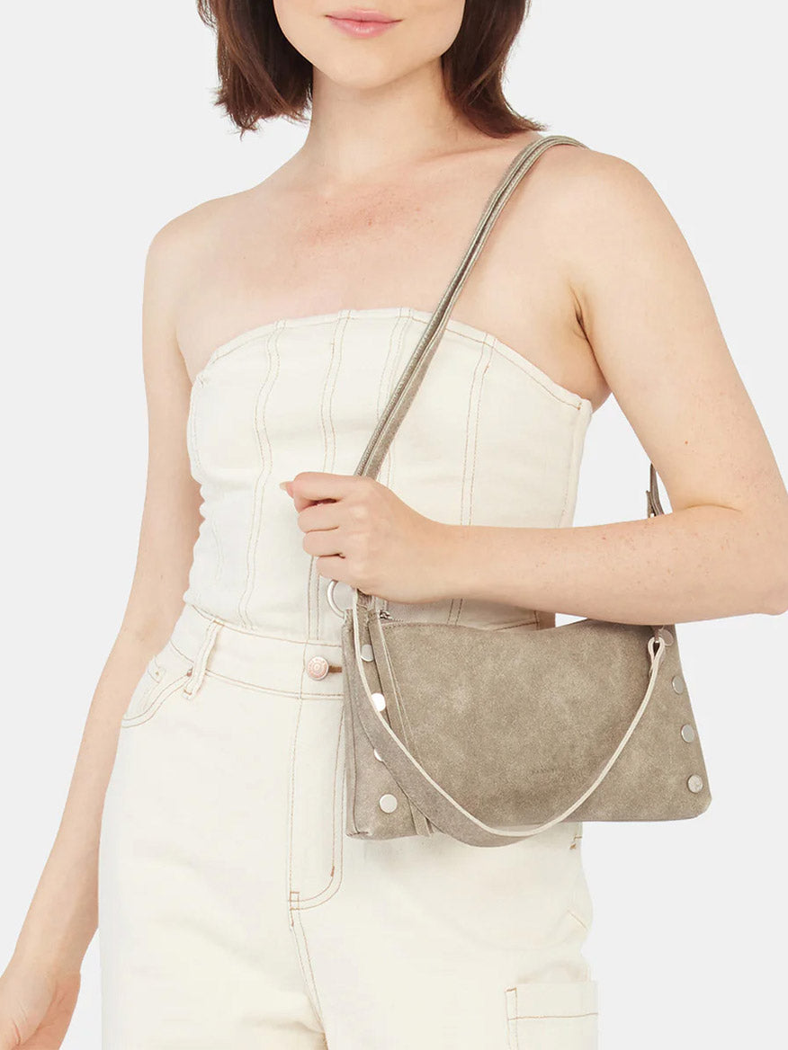 A person wearing an off-white strapless outfit holds a fresh Hammitt Los Angeles Kyle Shoulder Bag in Pewter, featuring a stylish crossbody strap.