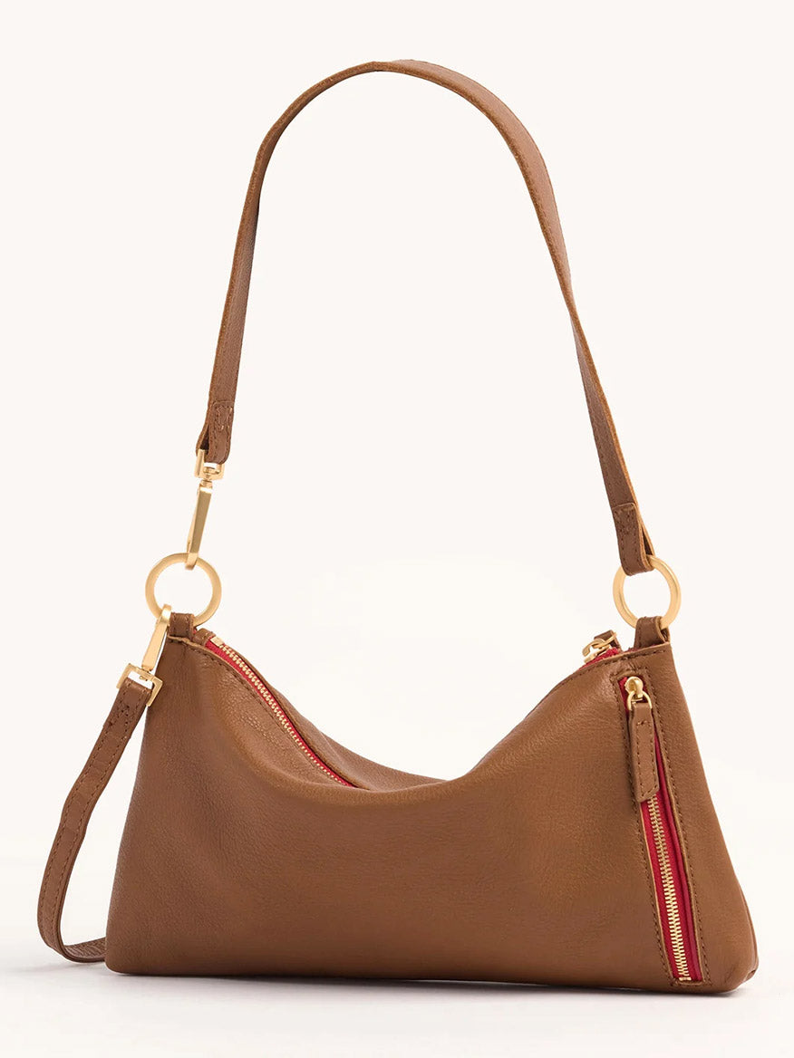 The Hammitt Los Angeles Kyle Shoulder Bag in Mahogany Pebble & Red Zip features brown pebbled leather, a gold zipper with red lining, a single shoulder strap with gold hardware, and stands out against the light background.