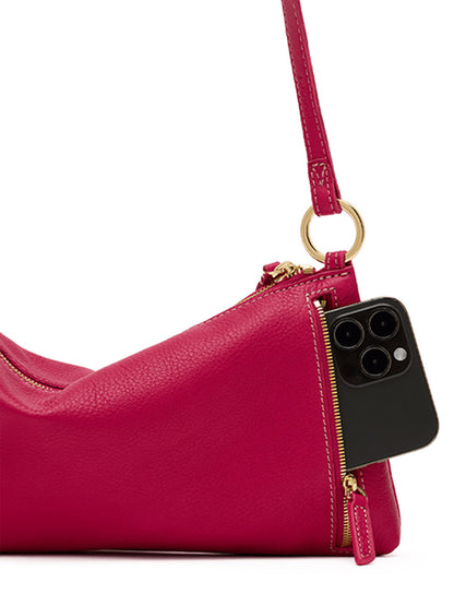A black smartphone partially fits inside the zippered pocket of the Hammitt Los Angeles Kyle Shoulder Bag in Calypso Pebble/Gold, a bright fuchsia pebbled leather crossbody bag with gold hardware.