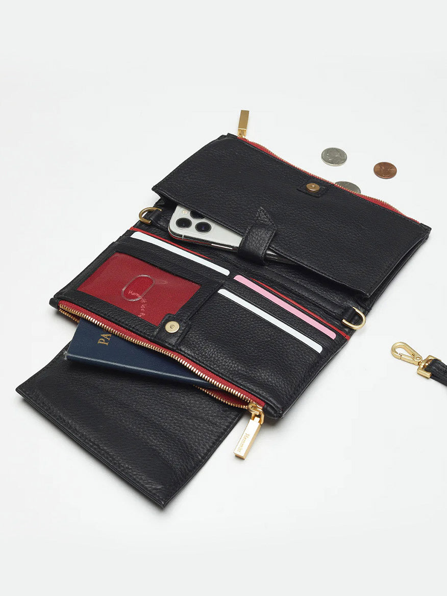 A Hammitt Los Angeles Levy Clutch in Black w/Red Zip with compartments for a smartphone, passport, cards, and some change sits nearby on a white background. Featuring organizational elements and a removable adjustable strap, it combines style with practicality.