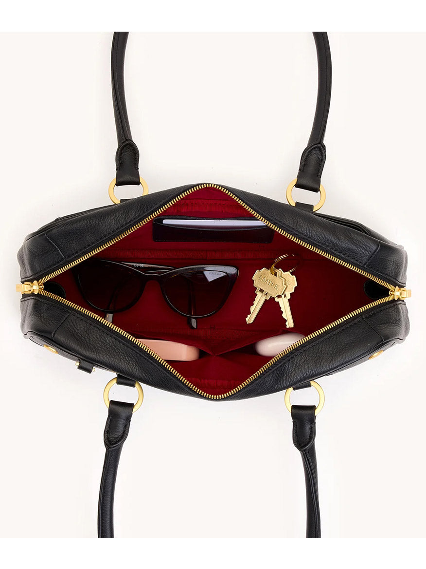 Top view of the Hammitt Los Angeles Meredith Small in Black/Brushed Gold, an open pebble leather handbag with red interior, holding sunglasses, keys, and wallet. This doctor-style bowling bag is crossbody ready for effortless style.