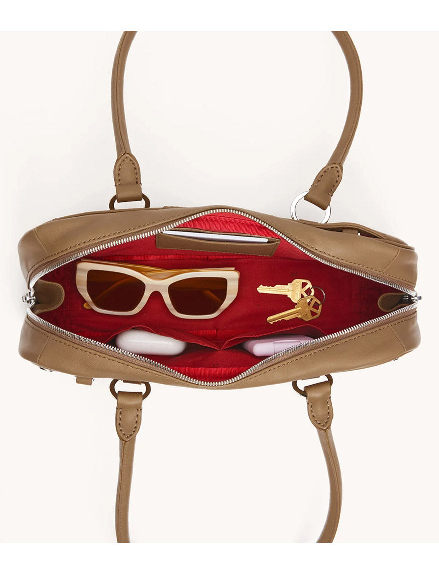 A Hammitt Los Angeles Meredith Small in Dune/Silver is unzipped to reveal sunglasses and two keys inside its red-lined interior.