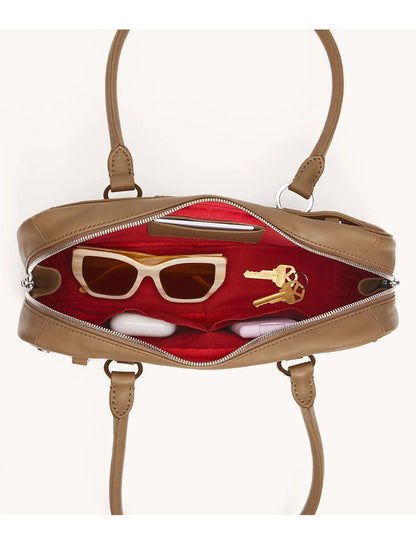 A Hammitt Los Angeles Meredith Small in Dune/Silver is unzipped to reveal sunglasses and two keys inside its red-lined interior.