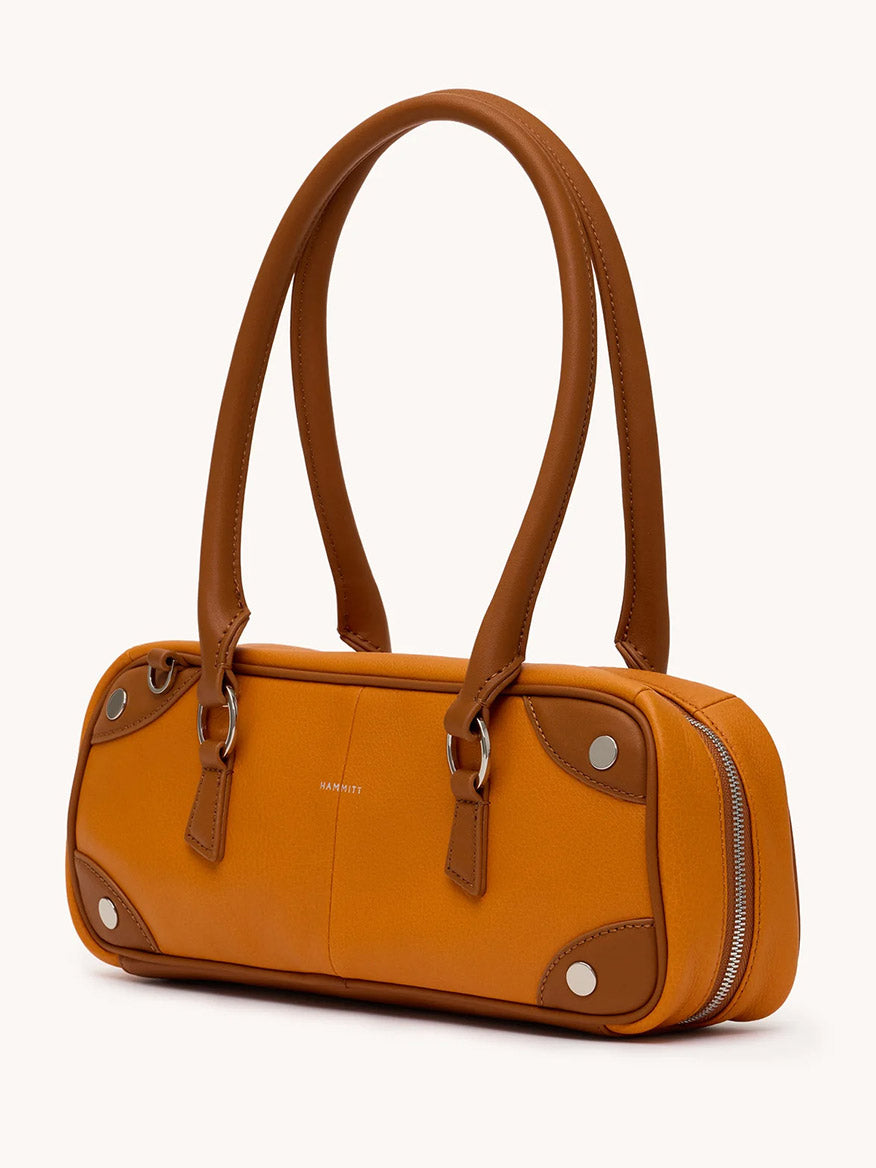 The Hammitt Los Angeles Meredith Small in Tailored Tangerine/Silver is a rectangular pebbled leather handbag with brown handles, corner accents, silver hardware, and a side zipper inspired by the classic Meredith bowling bag.