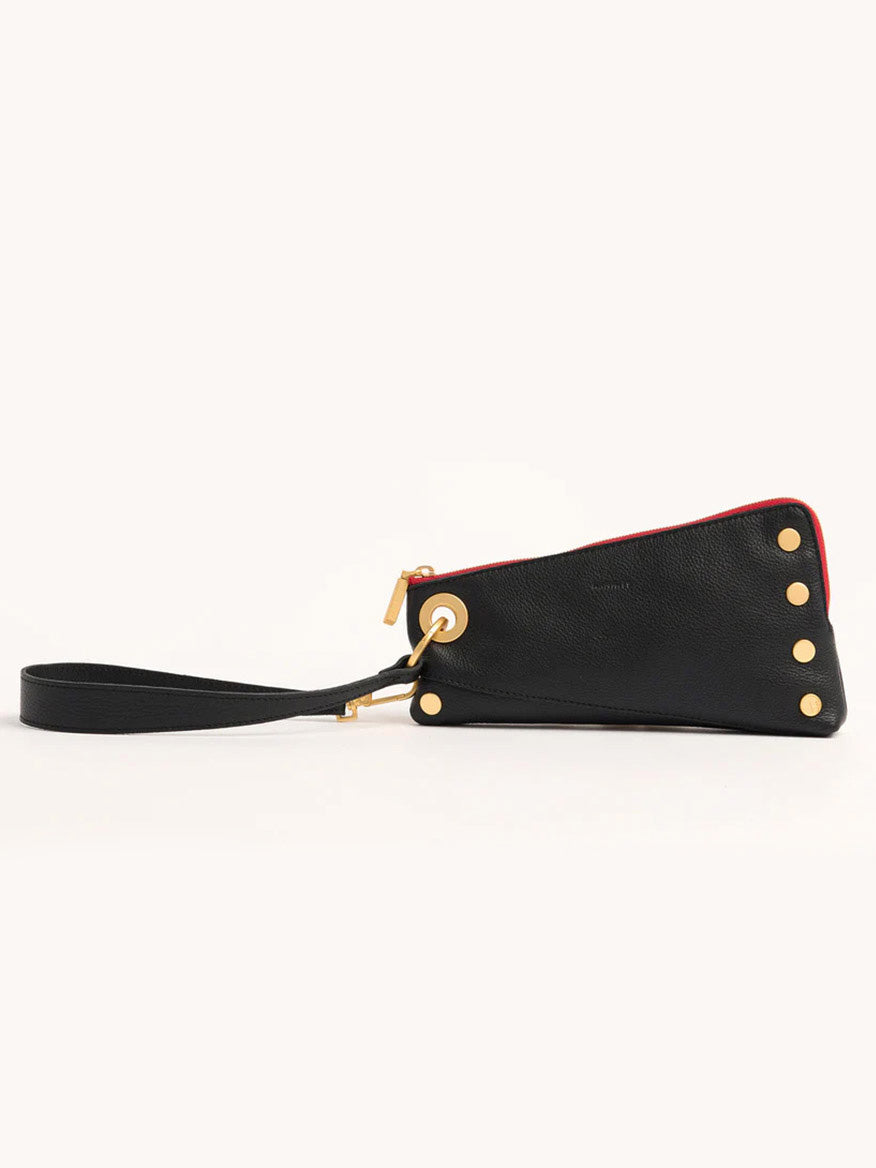 The Hammitt Los Angeles Nash Pochette in Black/Brushed Gold & Red Zip is a sophisticated black wristlet made from pebbled leather, featuring gold rivet accents and a red-trimmed gold zipper. Its adaptable design includes a detachable J-hook strap for enhanced convenience.