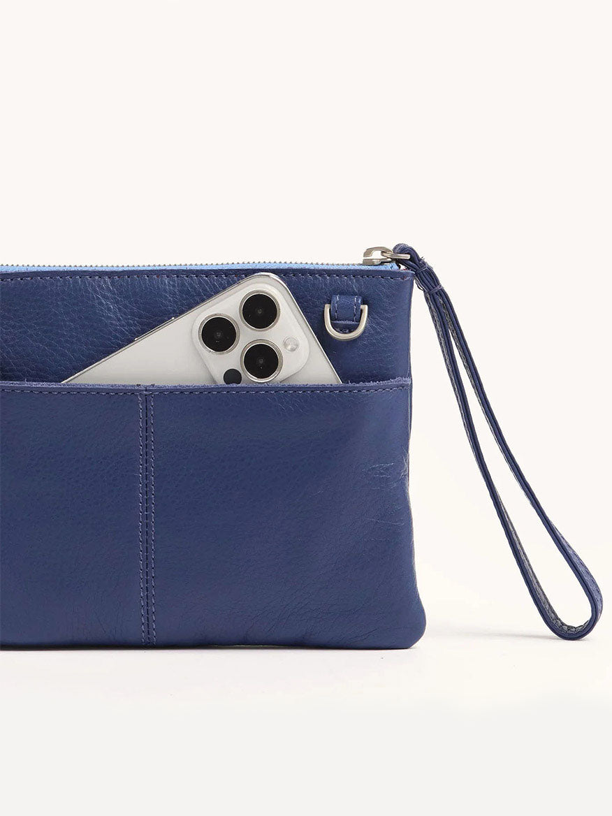 The Hammitt Los Angeles Nash Small Clutch in Jazz Blues showcases a smartphone partially visible in its blue pebbled leather pocket and includes a convertible strap for easy transformation into a crossbody bag.