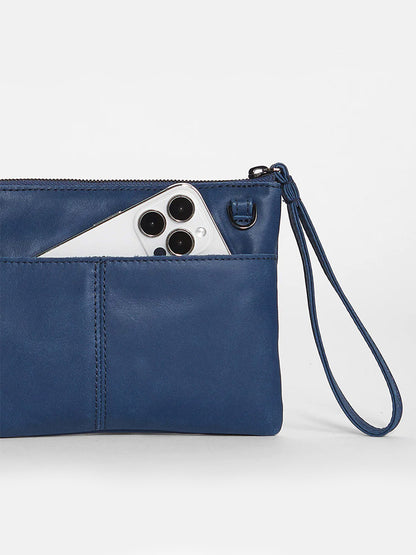 A smartphone peeking out from the Hammitt Los Angeles Nash Small Clutch in Vintage Navy, a navy clutch purse with a convertible strap.