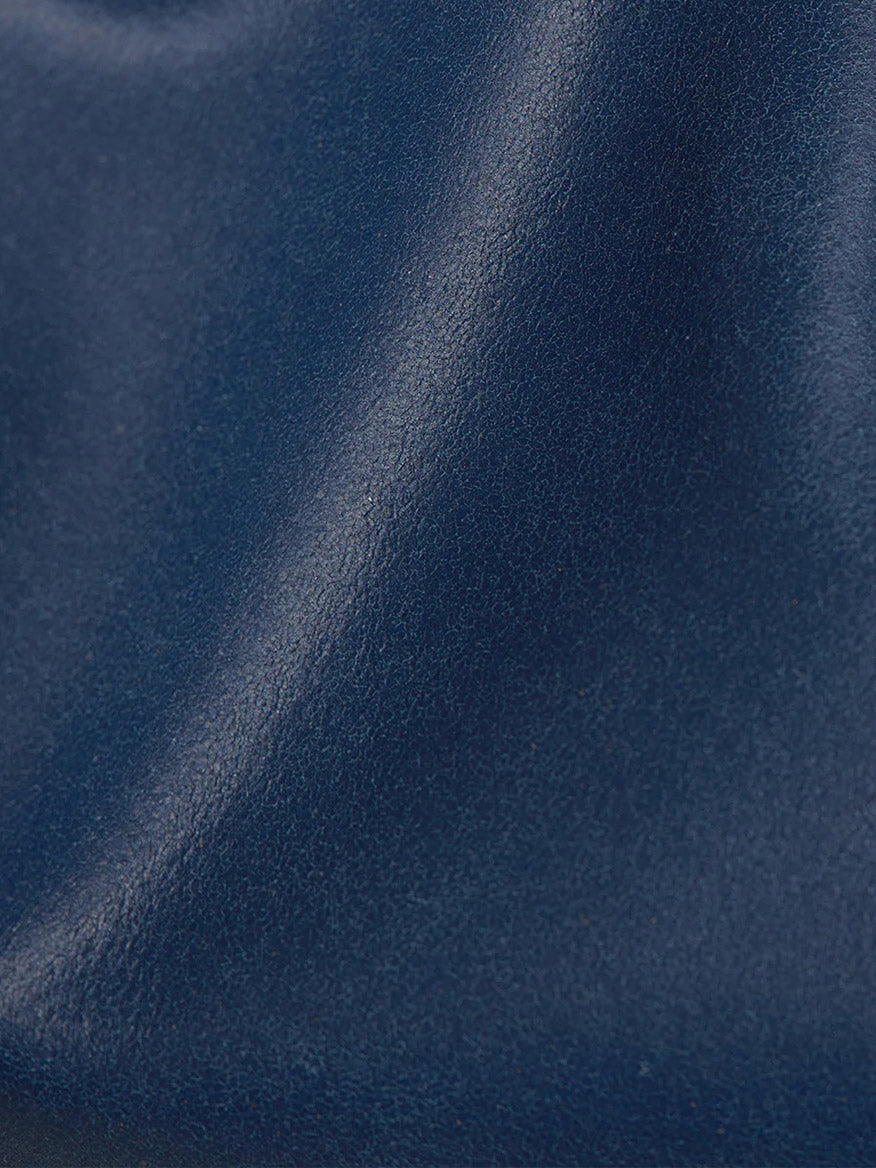 Close-up of a Navy blue leather texture with Hammitt Los Angeles Nash Small Clutch in Vintage Navy convertible strap.