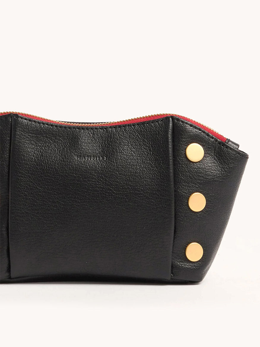 The Hammitt Los Angeles Paul Pocket in Black Press/Brushed Gold is a mini evening clutch made from Italian calf leather, featuring a red zipper and three gold buttons, shown against a light background.
