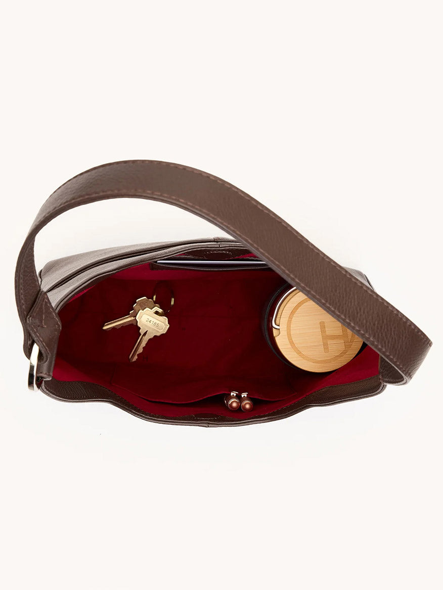 Top view of the Hammitt Los Angeles Tim Med Hobo in Espresso Pebble/Silver with red lining, shown open and containing a set of keys and a round wooden-lidded container.