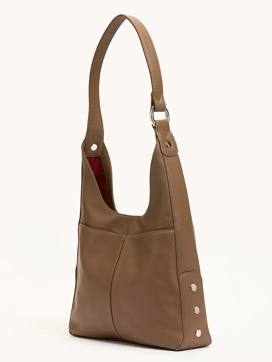 The Hammitt Los Angeles Tim Med Hobo in Dune/Silver is a leather hobo bag featuring a wide strap, silver rivet accents, and visible red lining.