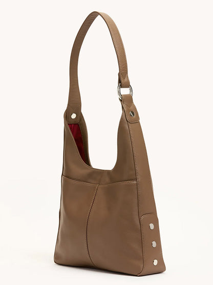 The Hammitt Los Angeles Tim Med Hobo in Dune/Silver is a leather hobo bag featuring a wide strap, silver rivet accents, and visible red lining.