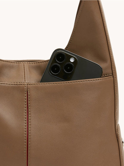 A black smartphone is partially visible inside the outer pocket of a stylish Hammitt Los Angeles Tim Med Hobo in Dune/Silver.
