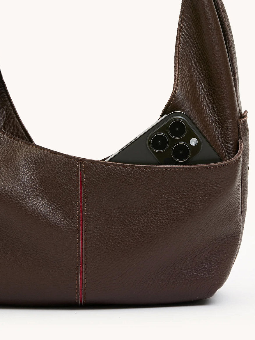 The Hammitt Los Angeles Tom Zip Medium in Espresso Pebble/Silver is a soft pebble leather handbag in espresso brown, shown with a visible pocket holding a black smartphone featuring three camera lenses.