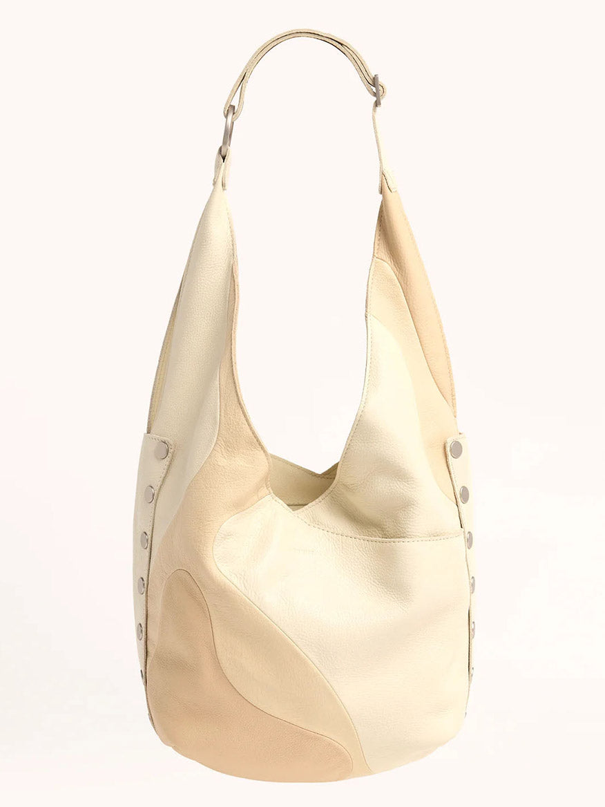 The Hammitt Los Angeles Tom Zip in Coastal Cream is a beige and cream patchwork Hobo bag with an adjustable strap and metal rivet details, perfect for those who love the Coastal Pebble aesthetic.