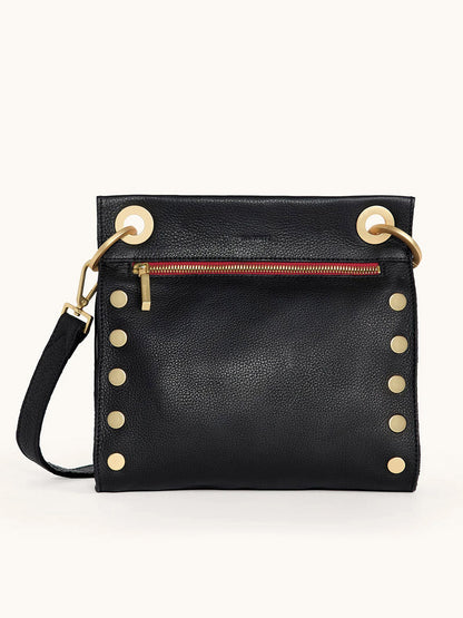 The Hammitt Los Angeles Tony Medium Crossbody Bag in Black/Brushed Gold/Red Zip features gold studs, a red zippered front pocket with gold hardware, and large gold grommets—perfect for everyday use.