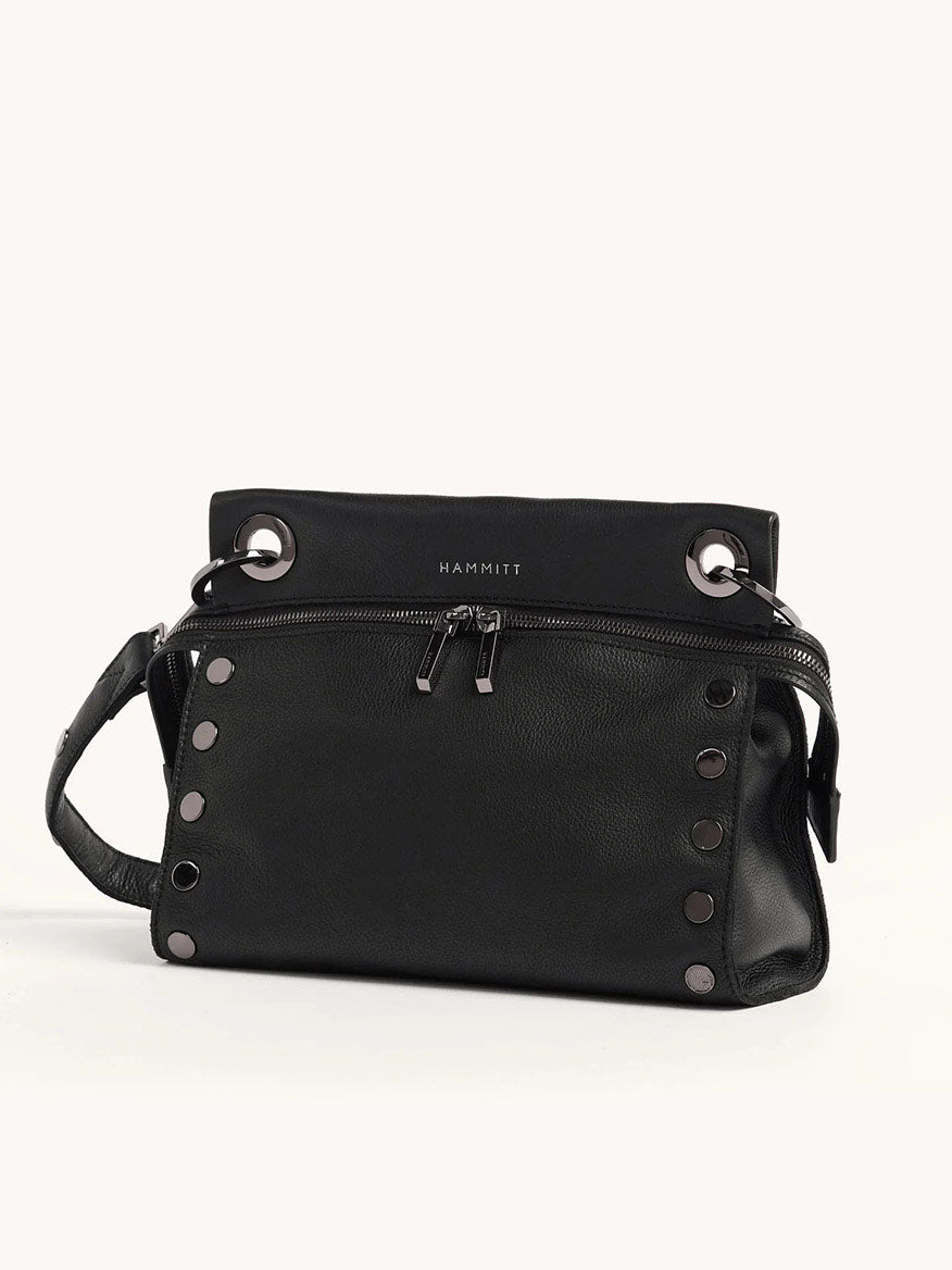 The Hammitt Los Angeles Tony Signature Medium Crossbody in Black & Gunmetal is a stylish pebbled leather handbag with metal grommets and studs, a zipper closure, and "Hammitt" on the top flap. It doubles as a crossbody bag with an adjustable strap for versatile wear.