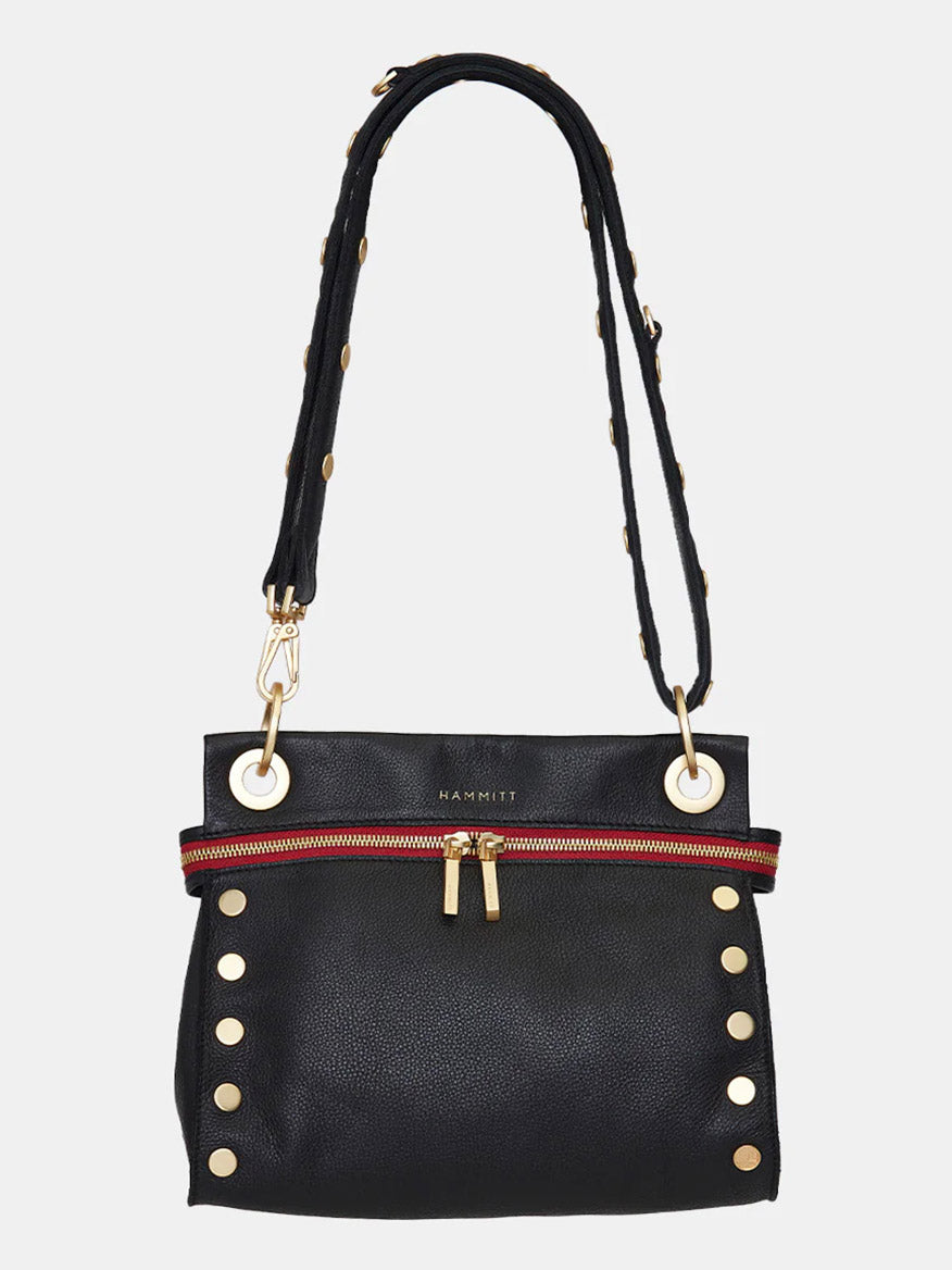 A black Hammitt Los Angeles Tony Signature Medium Crossbody in Black with gold studs, a red front zipper pocket, and gold hardware. The strap is adjustable, adorned with gold studs, and the brand name "HAMMITT" is visible on the front. This limited edition piece features commemorative details.