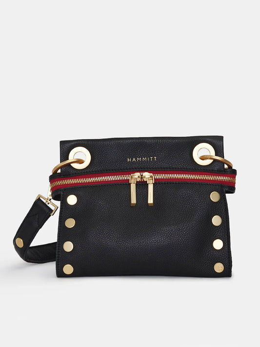 A black leather Hammitt Los Angeles Tony Signature Small Crossbody in Black with gold hardware, featuring large rivets and grommets, a red zipper accent, and an adjustable strap. The brand name "Hammitt" is displayed near the top.