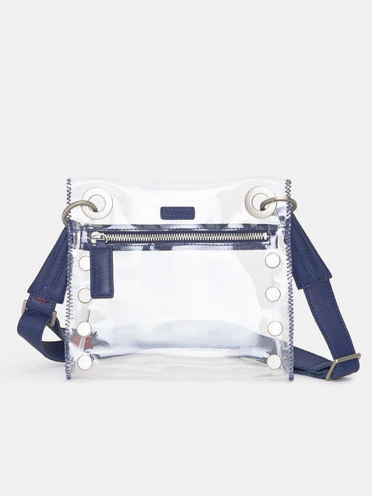 A Hammitt Los Angeles Tony Small Crossbody Bag in Clear Indigo with large metallic grommets and a navy-blue adjustable strap. The stadium-approved bag features a front zippered pocket and is accented with blue stitching.