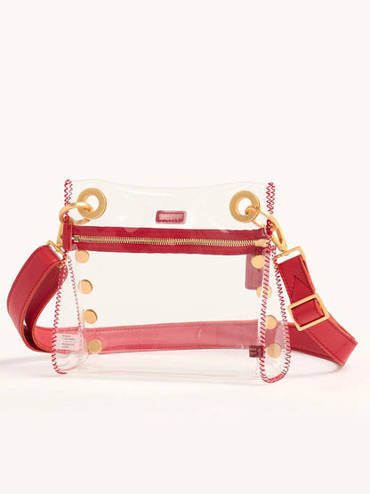 The Hammitt Los Angeles Tony Small Crossbody Bag in Clear Poppy Red is a stadium-approved handbag with red leather trim, gold circular accents, an adjustable crossbody strap, and red stitching.