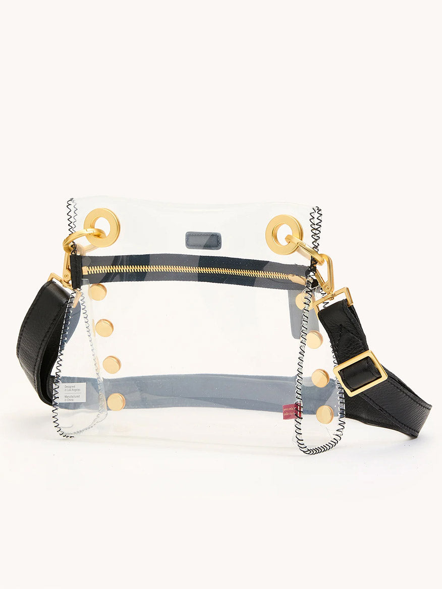 The Hammitt Los Angeles Tony Small Crossbody Bag in Clear Black/Brushed Gold features a transparent TPU and leather-trimmed body, gold grommets, chain detailing, black adjustable strap, gold zipper, and visible stitching for chic stadium-approved style.