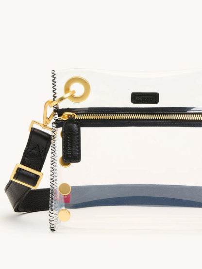 The Hammitt Los Angeles Tony Small Crossbody Bag in Clear Black/Brushed Gold is a stadium-approved TPU bag with leather trim, gold hardware, visible zipper pocket, metal accents, and a black adjustable crossbody strap.