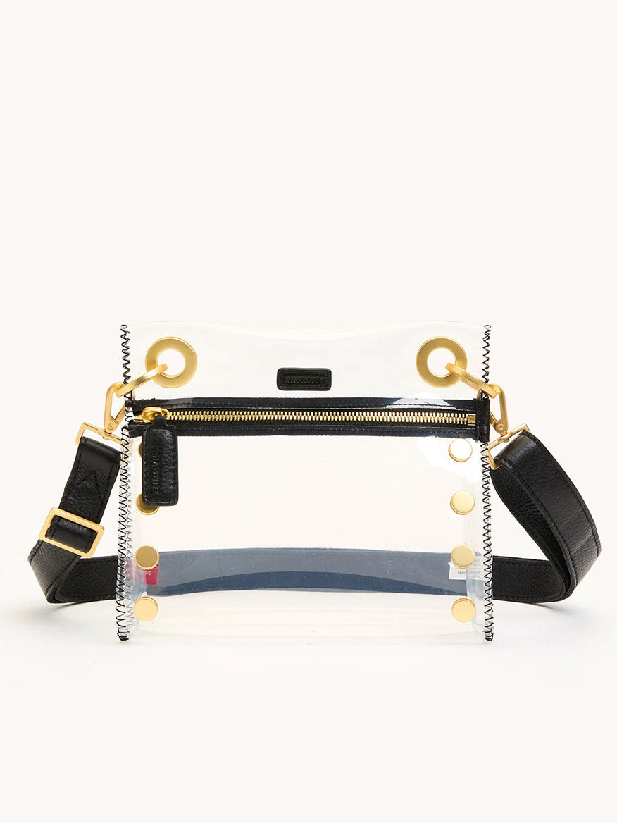 The Hammitt Los Angeles Tony Small Crossbody Bag in Clear Black/Brushed Gold features stadium-approved acrylic, TPU and leather trim, gold hardware, a front zipper pocket, and an adjustable strap, shown against a plain background.