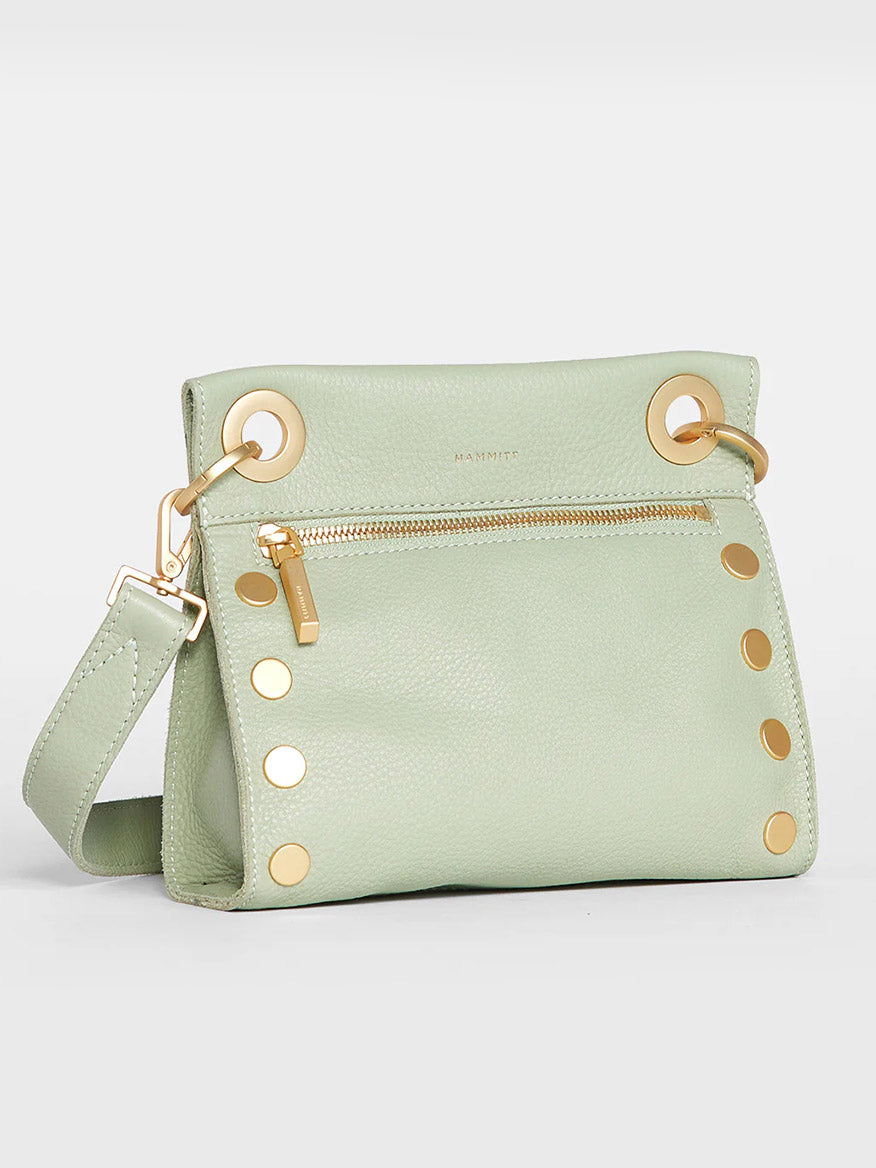 A Hammitt Los Angeles Tony Small Crossbody Bag in Cypress Sage with a gold zipper and rivet details, displayed against a light gray background.